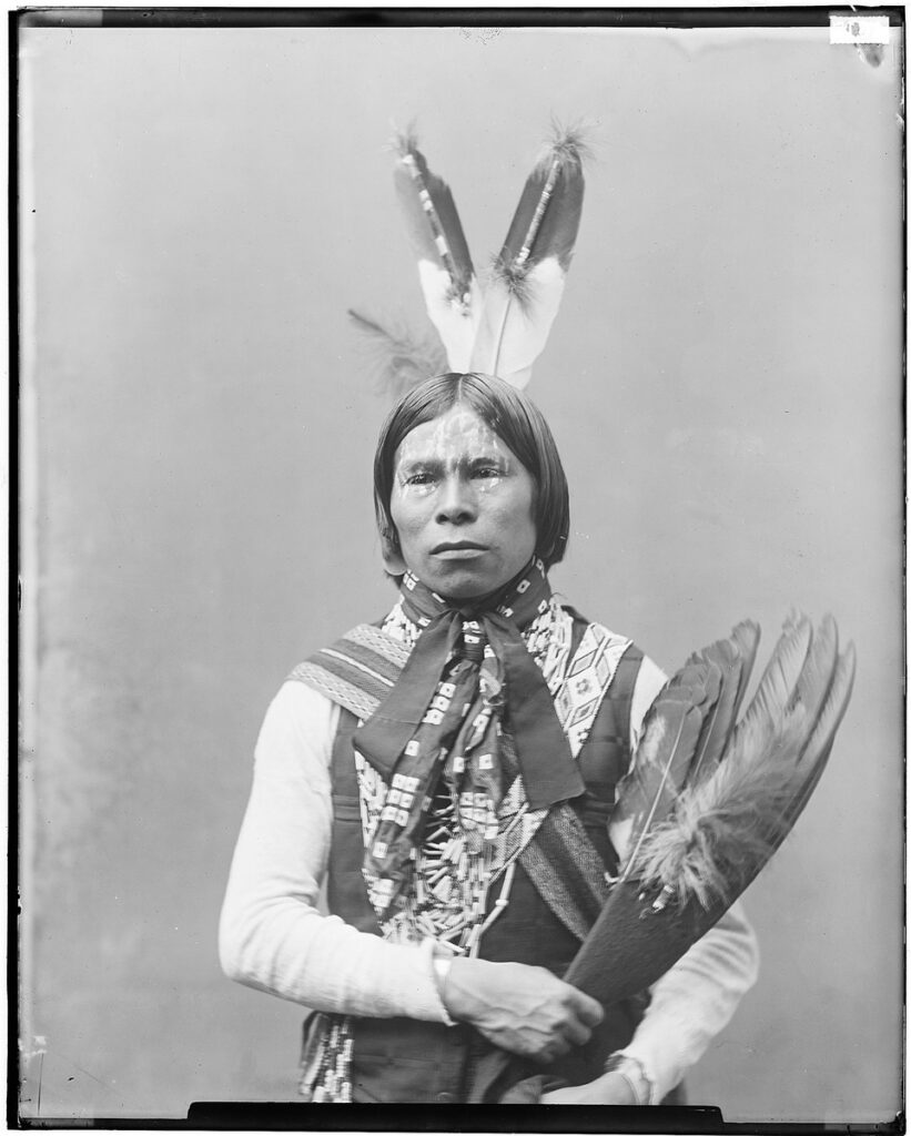Babe Shkit, a Kickapoo man wearing a feathered headdress
