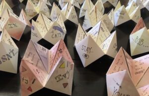 A collection of origami cootie catchers with messages and drawings