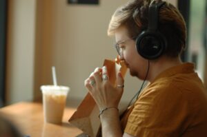 A person sits at a cafe wearing headphones and smells the aroma from a bag of coffee beans